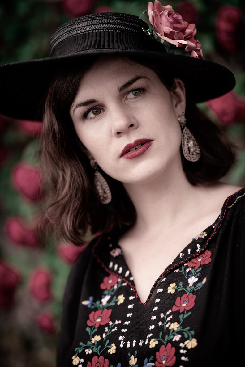 Beauty-Bloggerin RetroCat mit einem romantischen Vintage-Make-up, Vintage-Hut und Ethno-Ohrringen