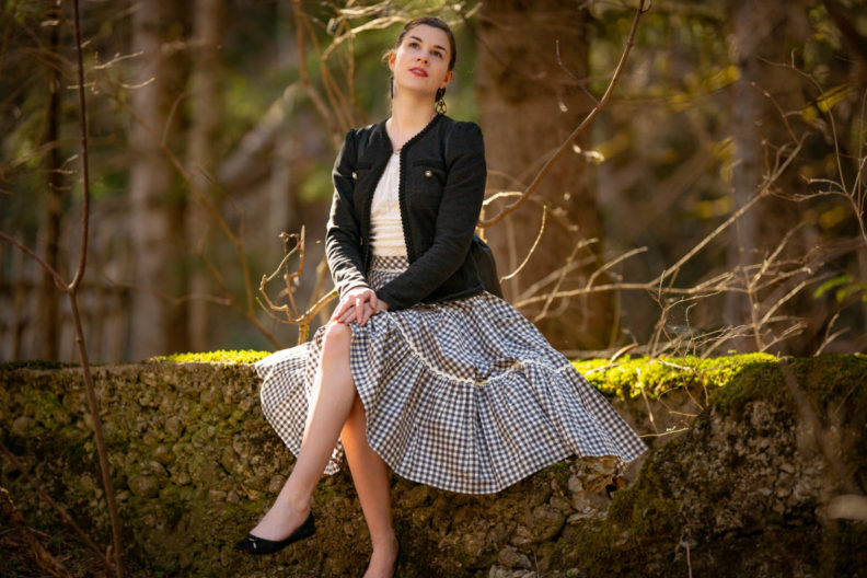 RetroCat wearing a romantic top, jacket, and plaid skirt in the forest