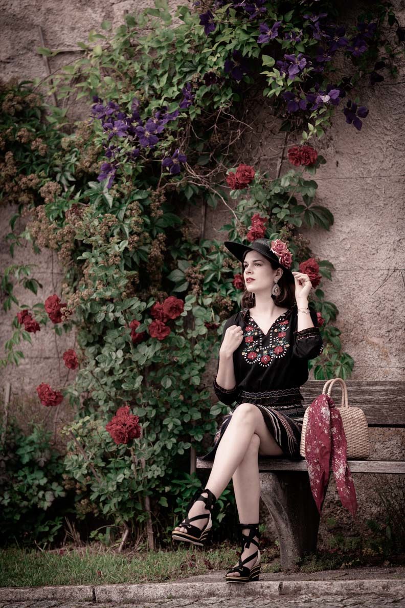 RetroCat mit Trachtenrock und ungarischer Bluse vor einer Rosenwand