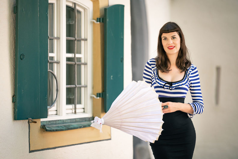 RetroCat with a parasol, corset ring, red lips, and a retro dress