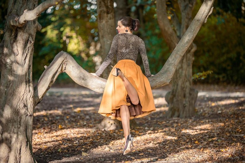 RetroCat climbing on a tree while wearing an autumn outfit with leopard print