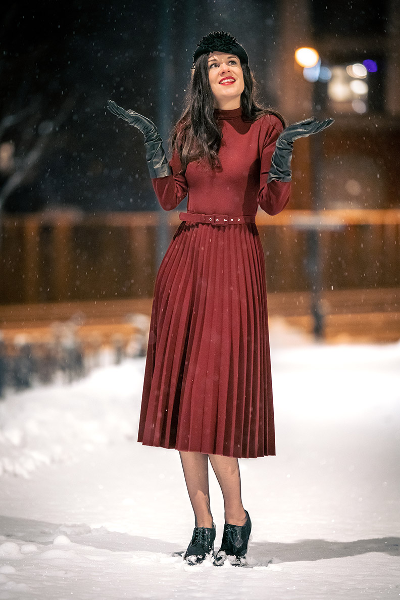 RetroCat trägt ein rotes Winterkleid und schwarze Handschuhe im Schnee