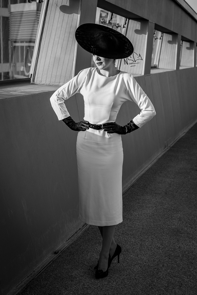 RetroCat wearing a white dress, big hat and long black gloves inspired by the New Look