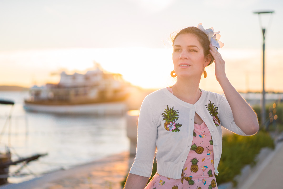 RetroCat trägt einen weißen Cardigan mit Ananas-Stickerei zum Ananas-Kleid im Urlaub