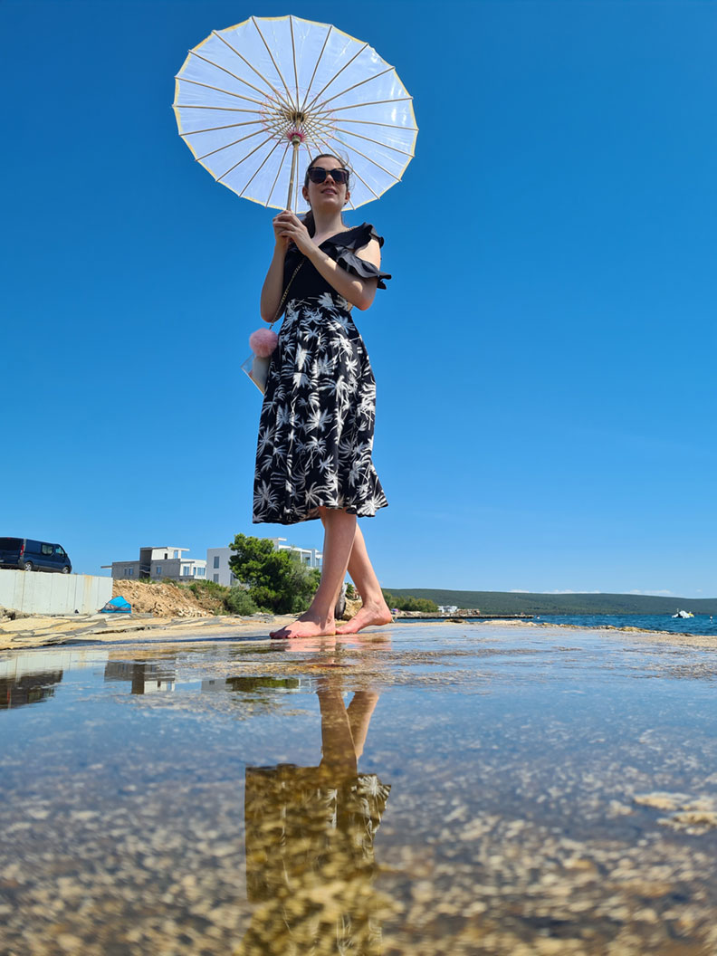 RetroCat in einem entspannten Strand-Outfit mit Palmenrock und Sonnenschirm