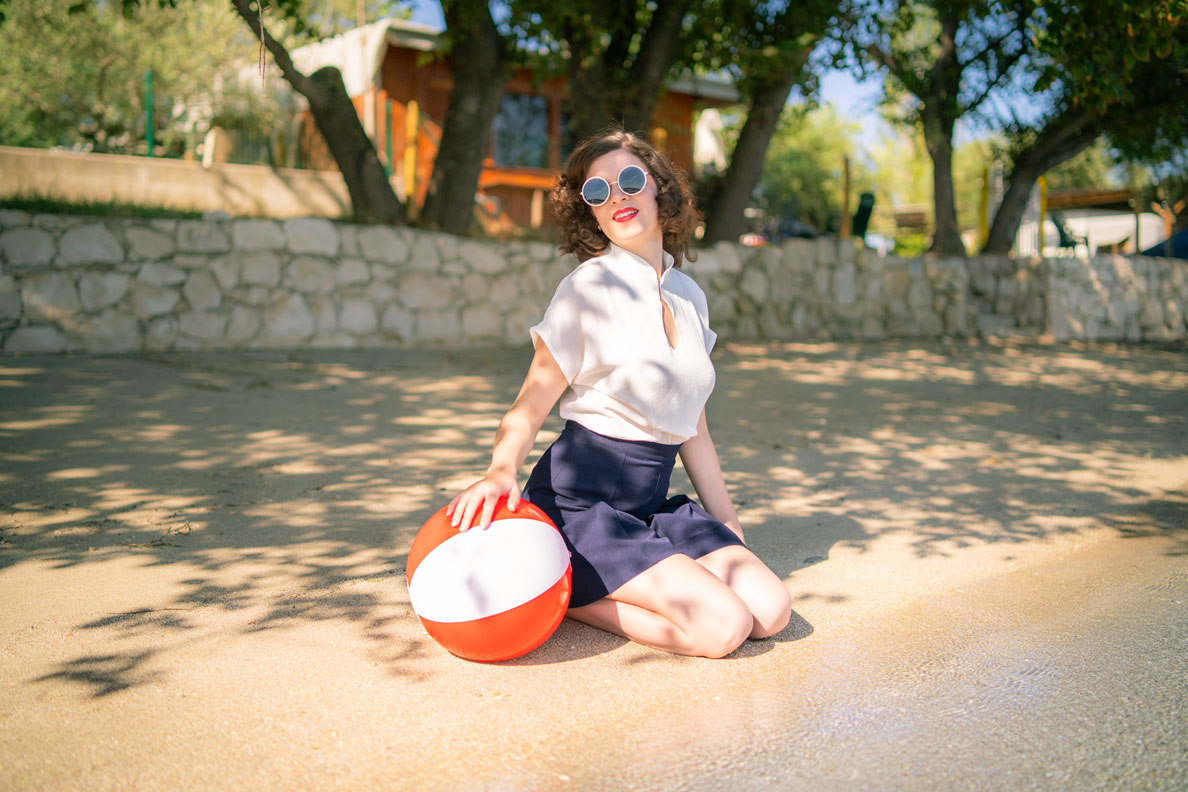 RetroCat wearing retro shorts and a white blouse at the beach