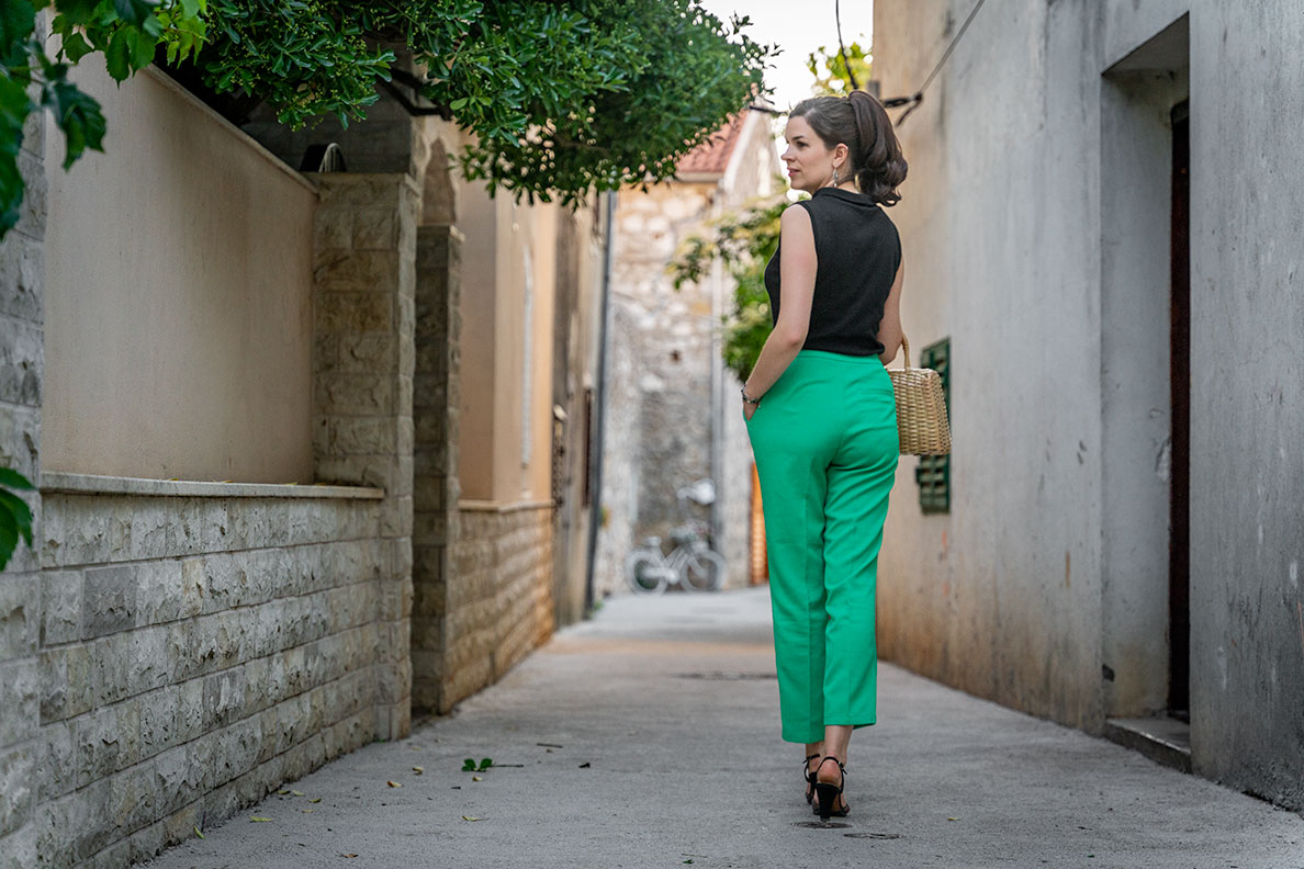 RetroCat wearing green trousers and a black top in an old town