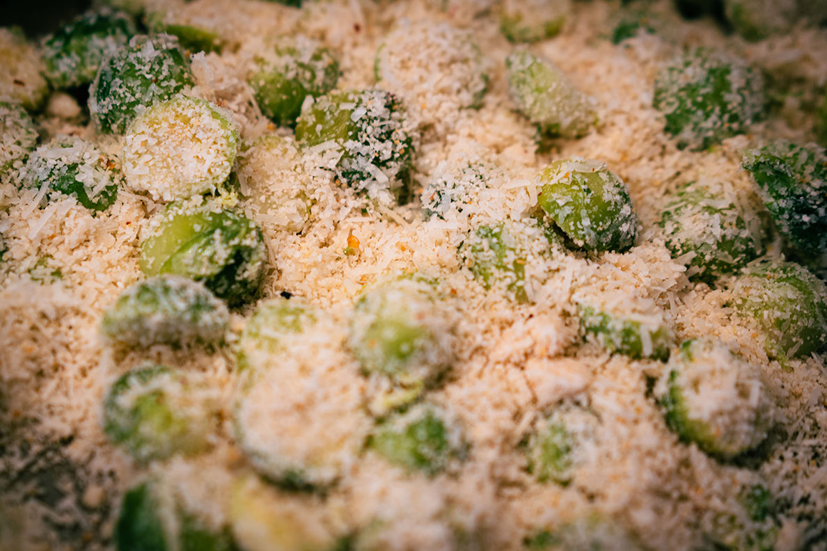 Der mit Parmesan, Knoblauch und Chili marinierte Rosenkohl auf einem Backblech