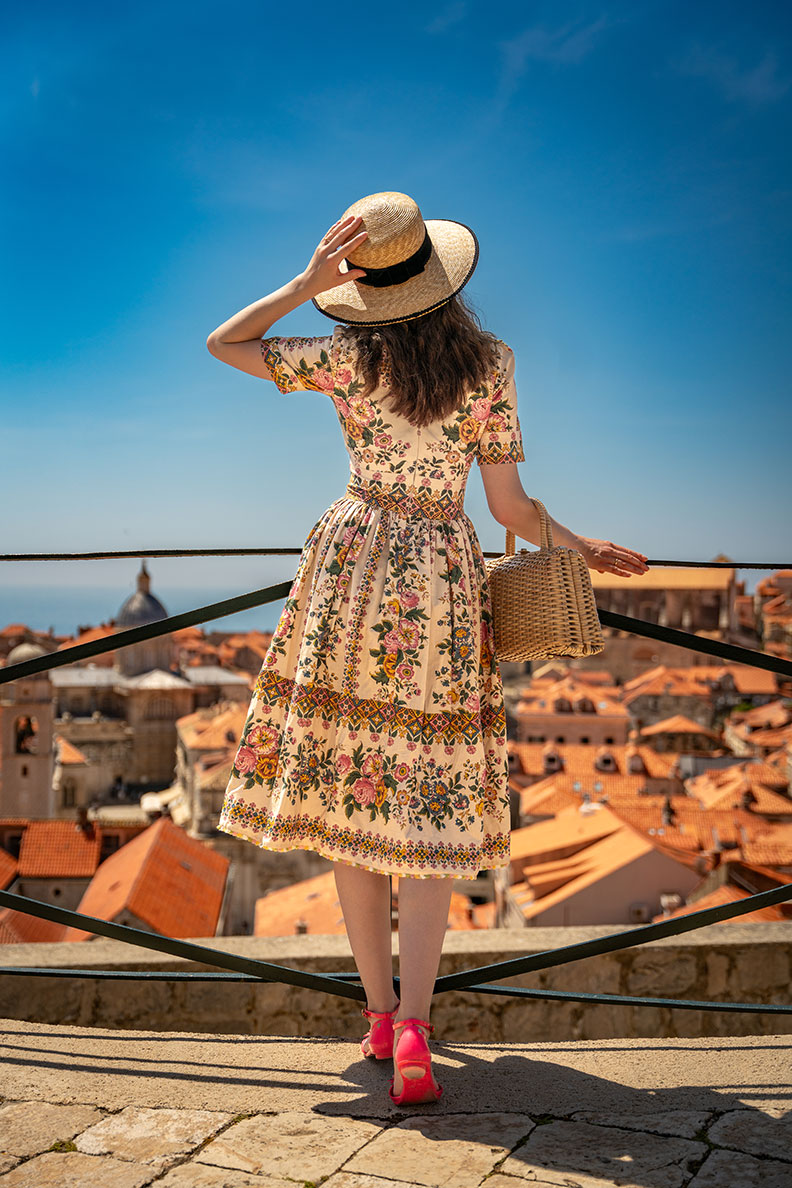 RetroCat trägt ein Retro-Kleid mit Blumenmuster, einen Strohhut und eine Korbtasche in Dubrovnik