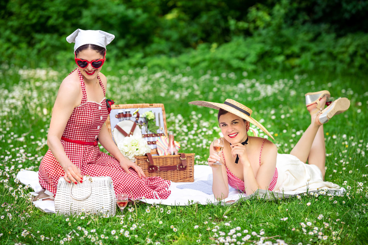 RetroCat and her friend in red and white gingham outfits at a picnic