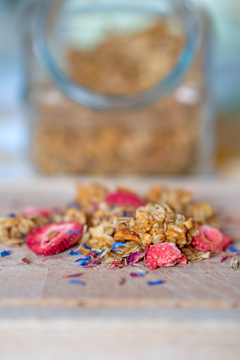Selbstgemachtes Frühlings-Knuspermüsli mit essbaren Blüten und Erdbeeren