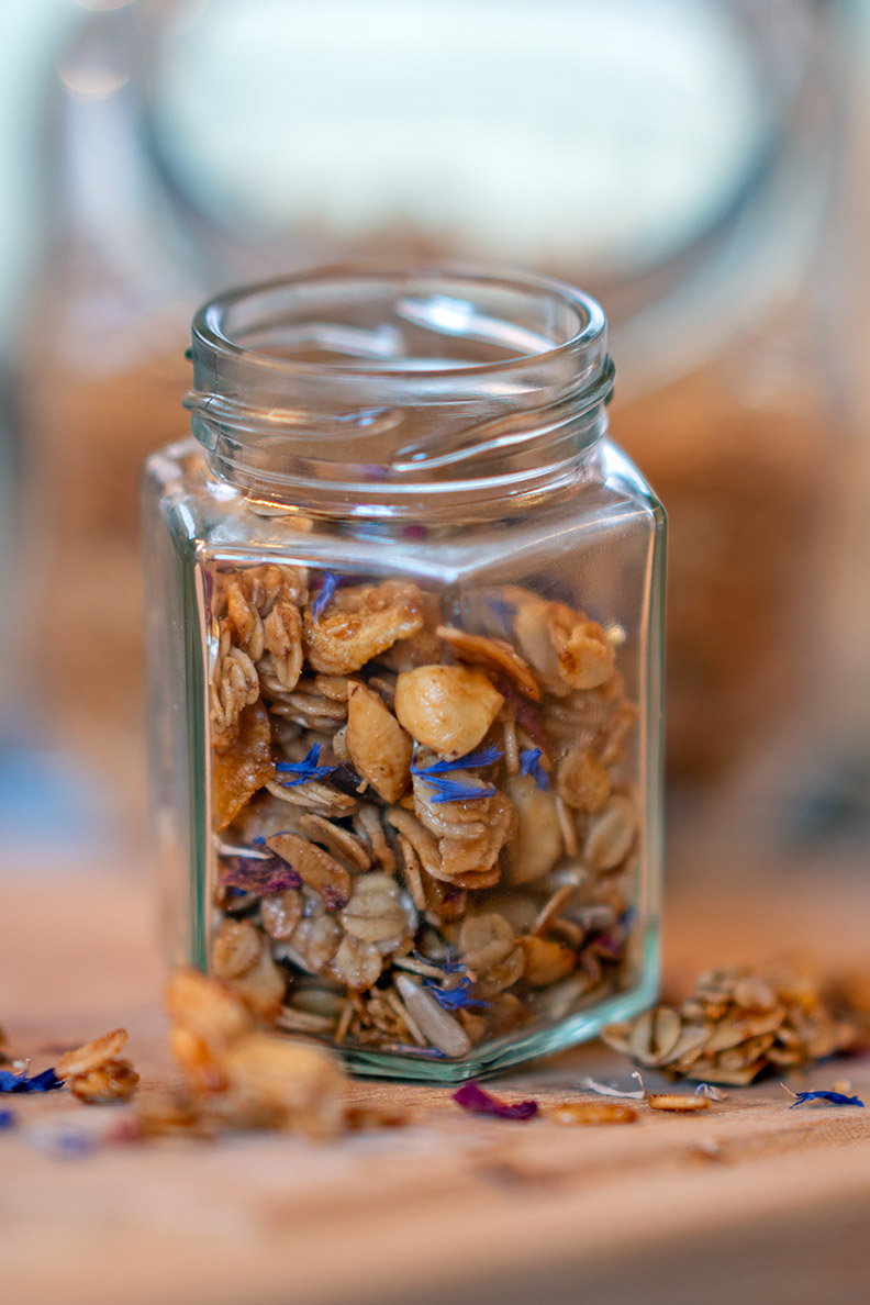 Selbstgemachtes Granola mit Blüten in einem kleinen Glas