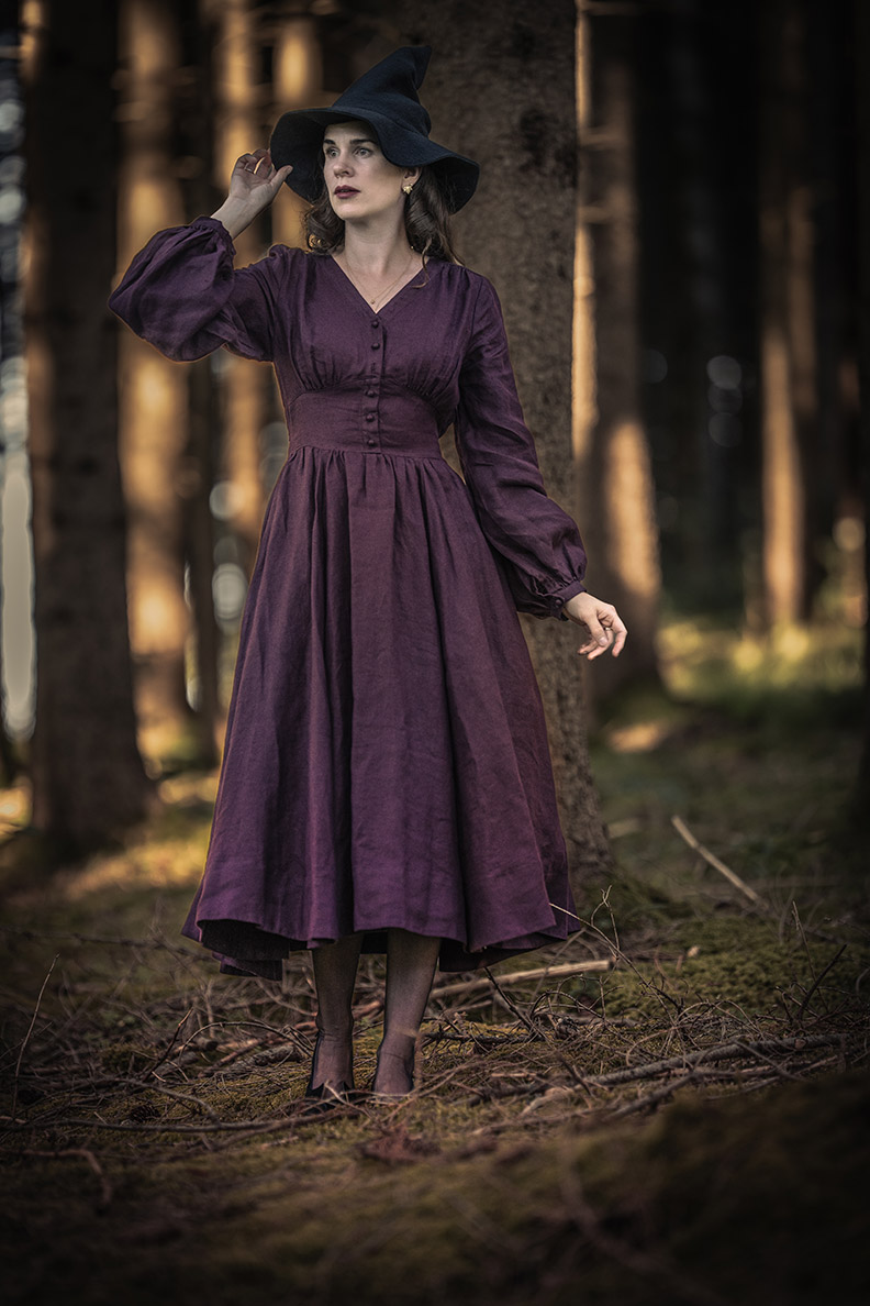 RetroCat in a plum-colored linen dress in the forest