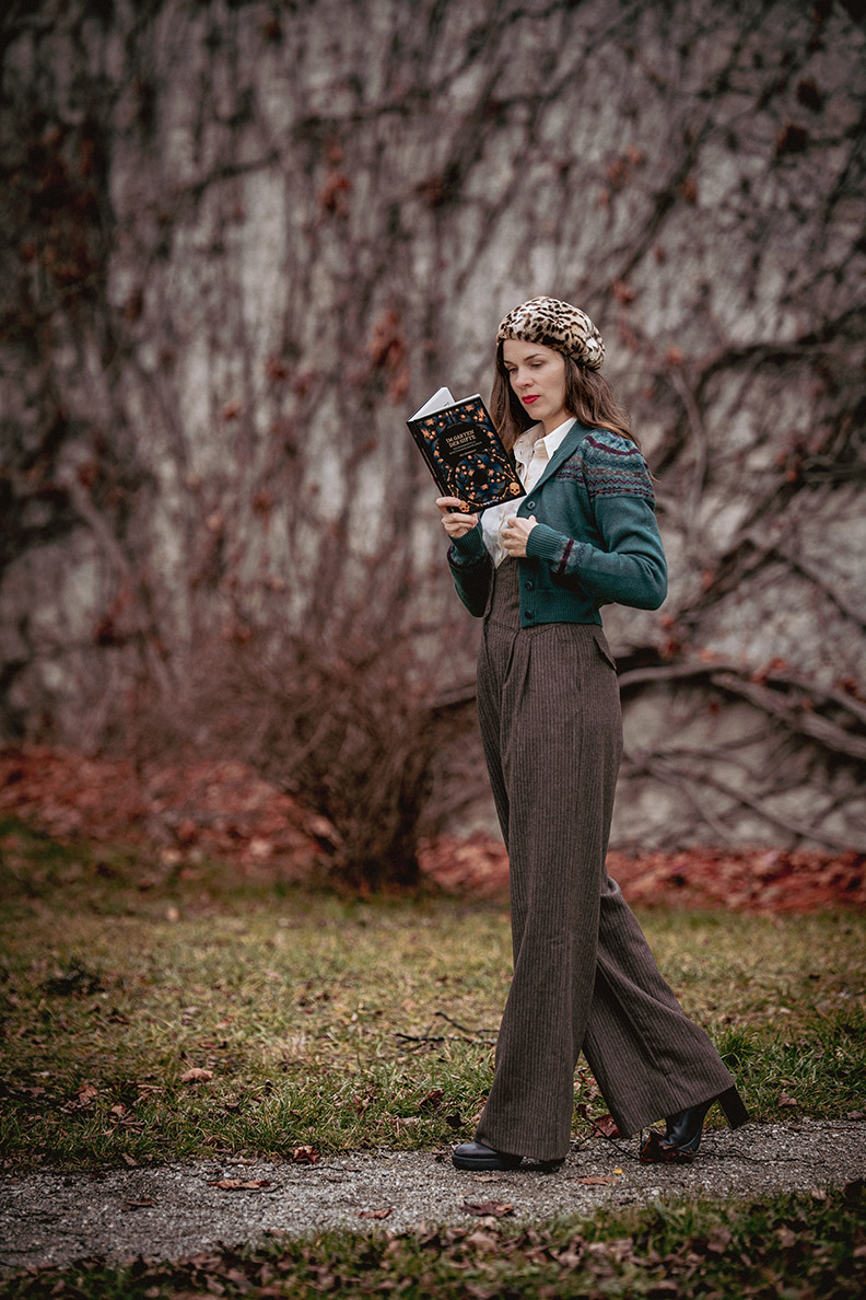 RetroCat mit weiten Vintage-Hosen und einem Cardigan beim Lesen