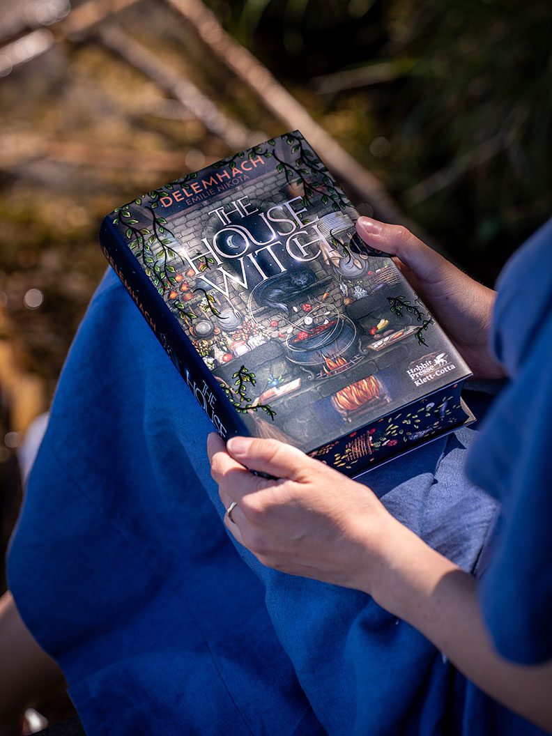 RetroCat mit dem Buch "The House Witch" in der Natur